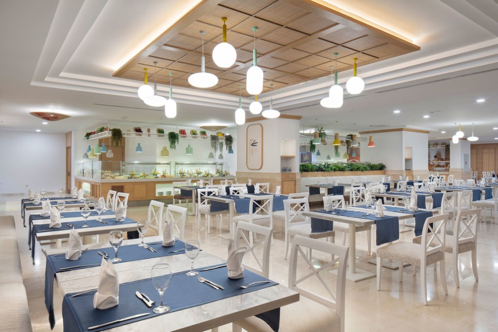 Salle de restaurant avec comptoirs buffet et tables dressées.