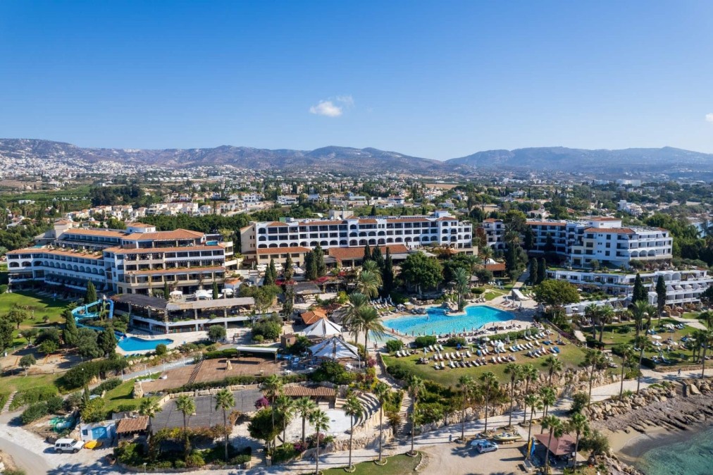 Vue panoramique des bâtiments du complexe, piscines et zone côtière avec montagnes au loin