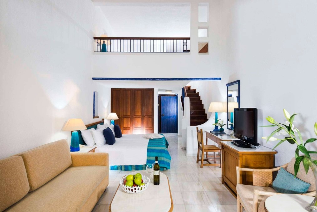 Chambre duplex avec lit, coin salon et escalier, idéale pour l'hébergement lors d'un stage sportif