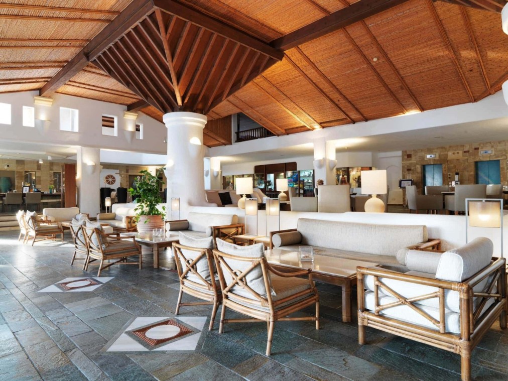 Hall d'hôtel lumineux avec fauteuils en rotin, canapés blancs et design ouvert adapté aux rassemblements d'équipe