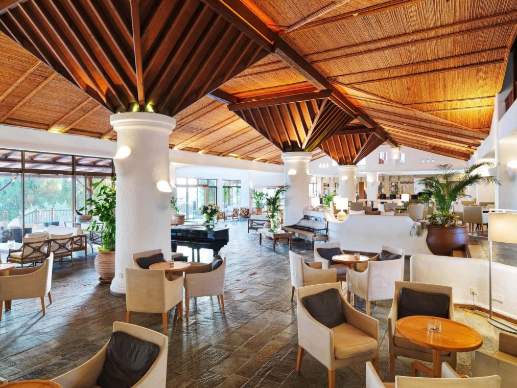 Salon d'hôtel spacieux avec plafond en bois, mobilier moderne et lumière naturelle près des installations de stage