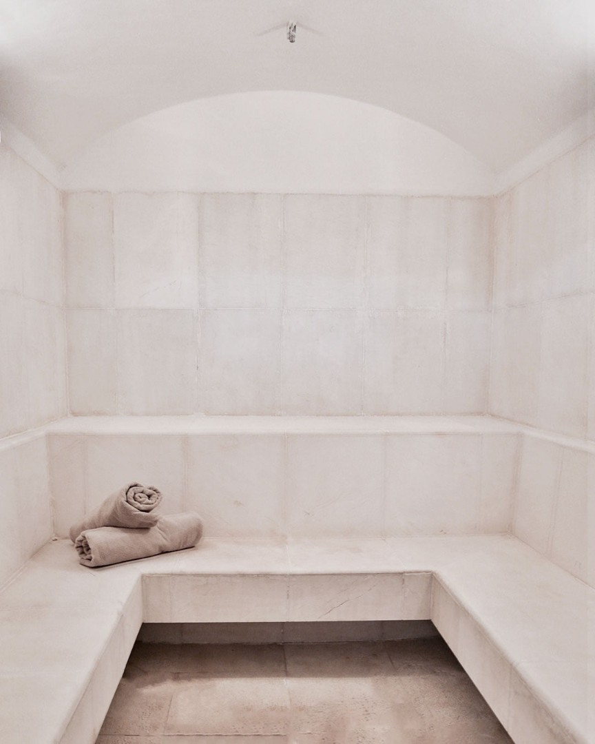 Hammam lumineux avec bancs carrelés et serviettes roulées pour la récupération des athlètes