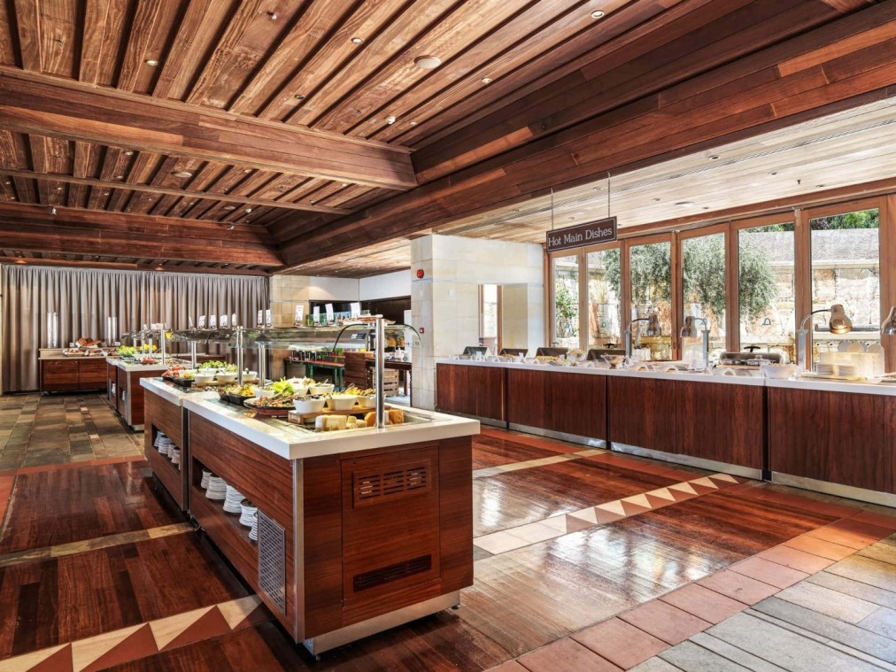 Restaurant buffet avec intérieur en bois, comptoirs de service et lumière naturelle abondante