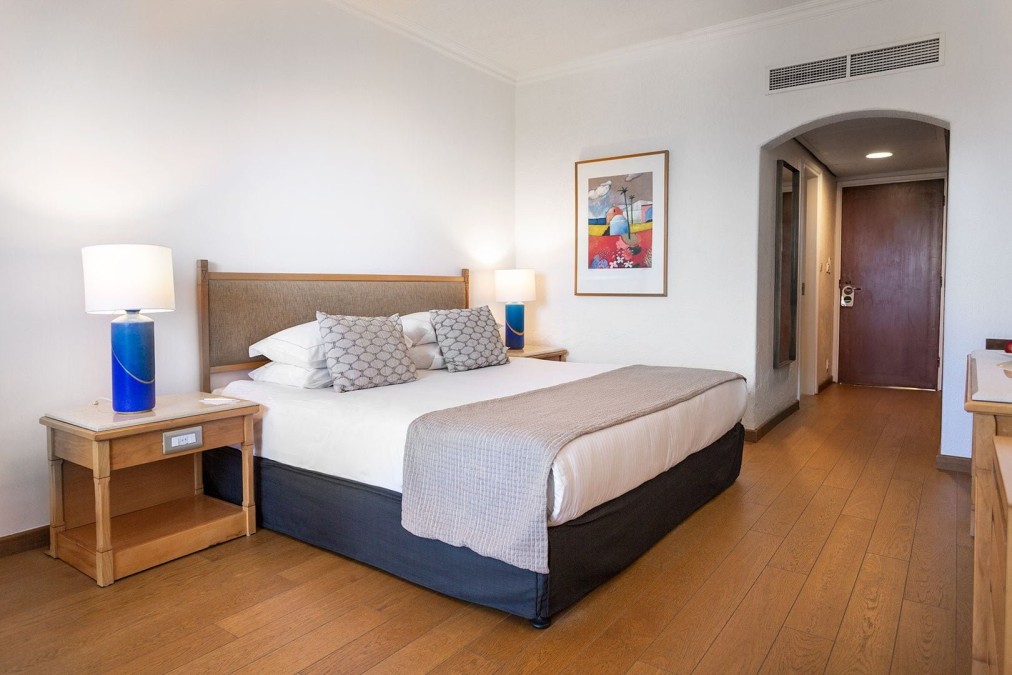 Chambre confortable avec lit king-size, lampes de chevet et décoration minimaliste pour l'hébergement des athlètes