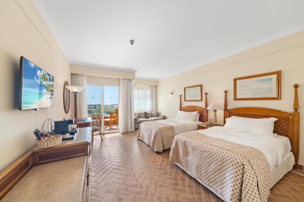 Chambre spacieuse avec lits jumeaux, TV et vue sur balcon pour séjours prolongés.