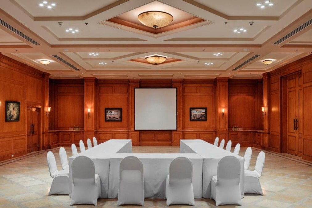 Salle de réunion lambrissée avec tables en U et écran de projection pour briefing d'équipe de stage d'entraînement