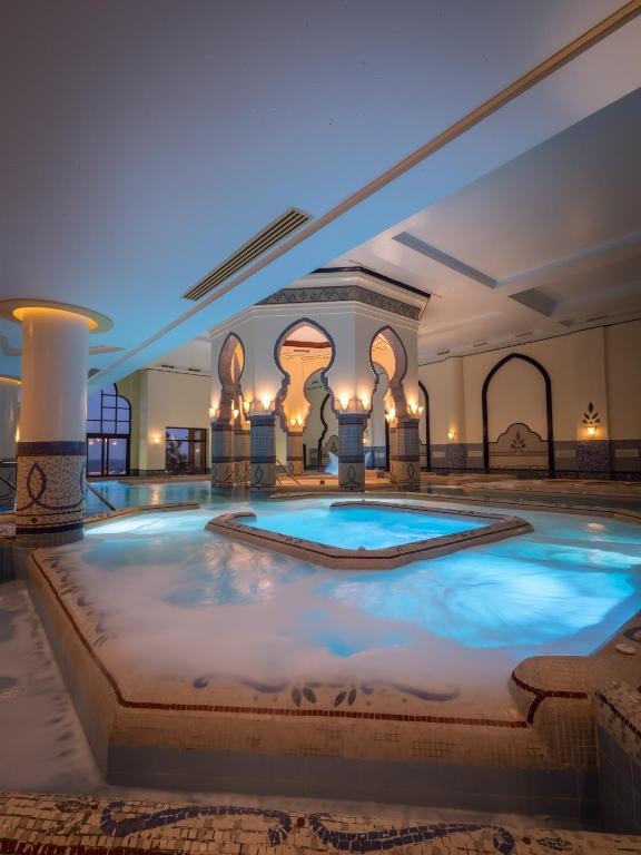 Piscine thalasso intérieure avec arches de style mauresque et éclairage doux du soir pour relaxation et récupération