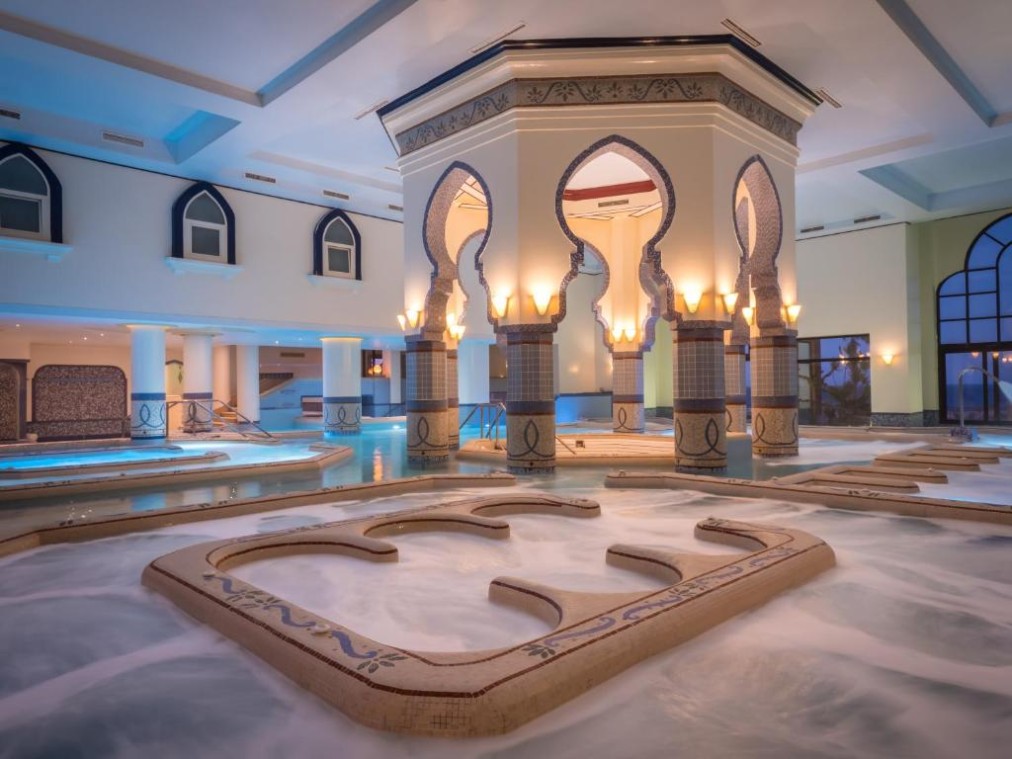 Espace jacuzzi/thalasso intérieur avec eau mousseuse et arches spectaculaires, environnement relaxant de récupération