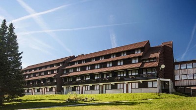 Vue extérieure du bâtiment de l'hôtel avec balcons, toit en pente et pelouse verte environnante.