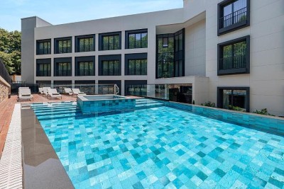 Piscine extérieure dans la cour de l'hôtel avec chaises longues et terrasse.