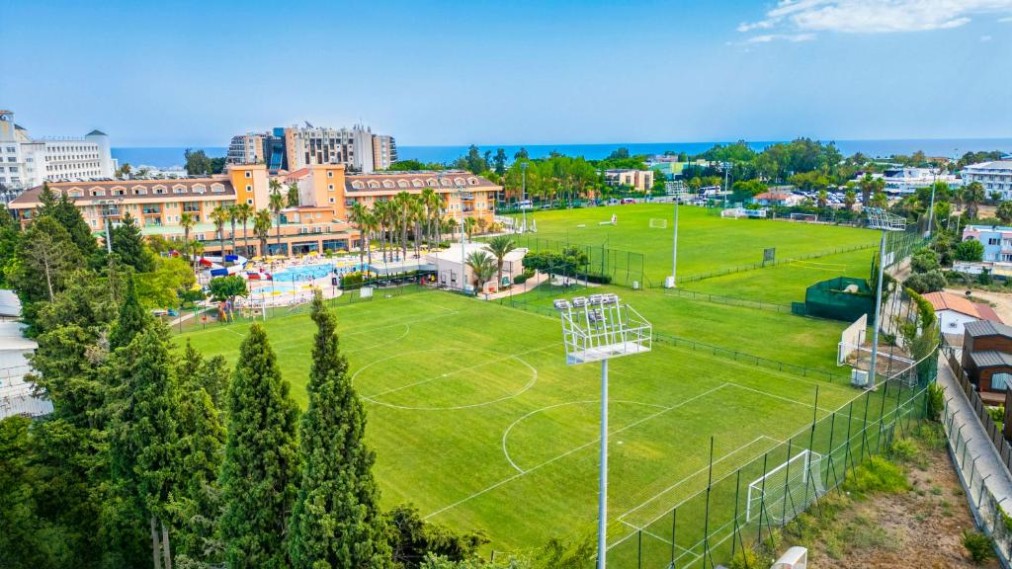 Vue aérienne de la zone du complexe avec deux terrains de football et bâtiments environnants près de la côte.