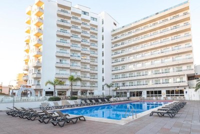 Extérieur de l'hôtel avec piscine extérieure et transats dans la cour