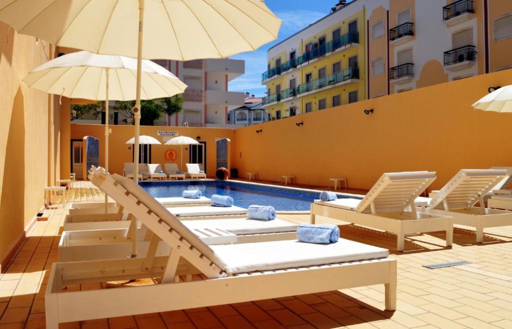 Transats et parasols au bord de la piscine extérieure dans la cour.
