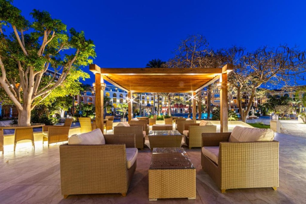 Espace lounge extérieur avec canapés en osier sous pergola en bois la nuit