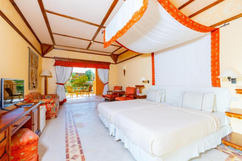 Chambre d'hôtel spacieuse avec lit à baldaquin, touches rouges et accès au balcon