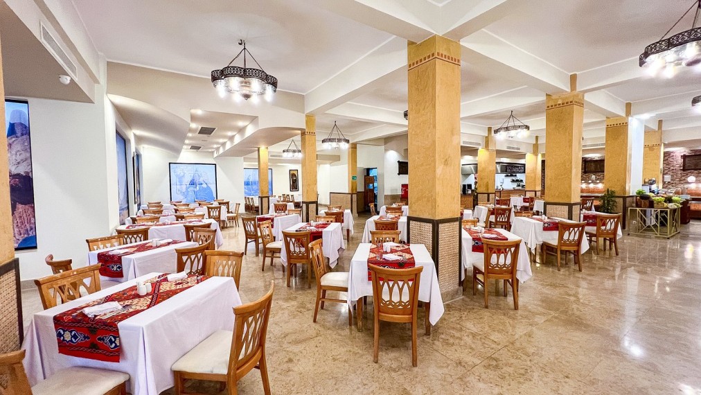 Restaurant spacieux avec chaises en bois, nappes blanches et éclairage chaleureux, idéal pour les repas de groupe après les sessions d'entraînement