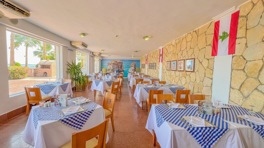 Salle à manger lumineuse avec nappes à carreaux bleus, grandes fenêtres et décoration murale en pierre
