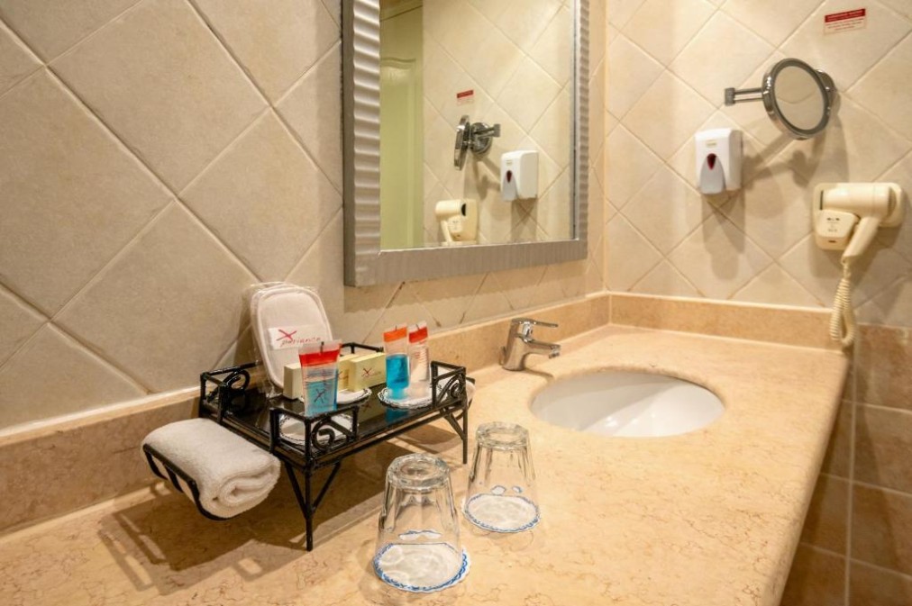 Plan de travail de salle de bain avec lavabo, articles de toilette et miroir dans un décor carrelé