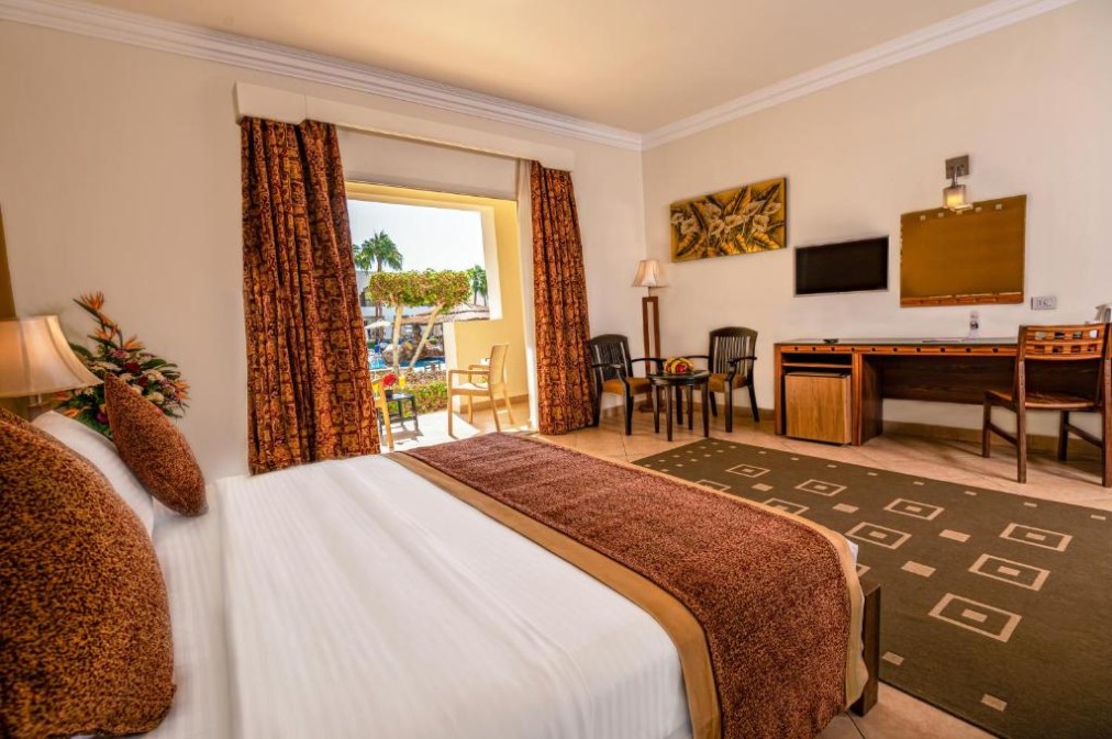 Chambre confortable avec lit double, bureau de travail et vue sur la piscine par la porte-fenêtre coulissante