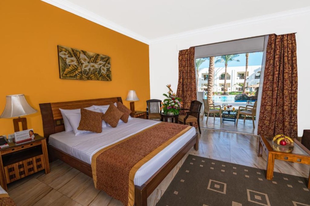 Chambre d'hôtel avec lit king-size, décoration chaleureuse et accès direct à la terrasse au bord de la piscine