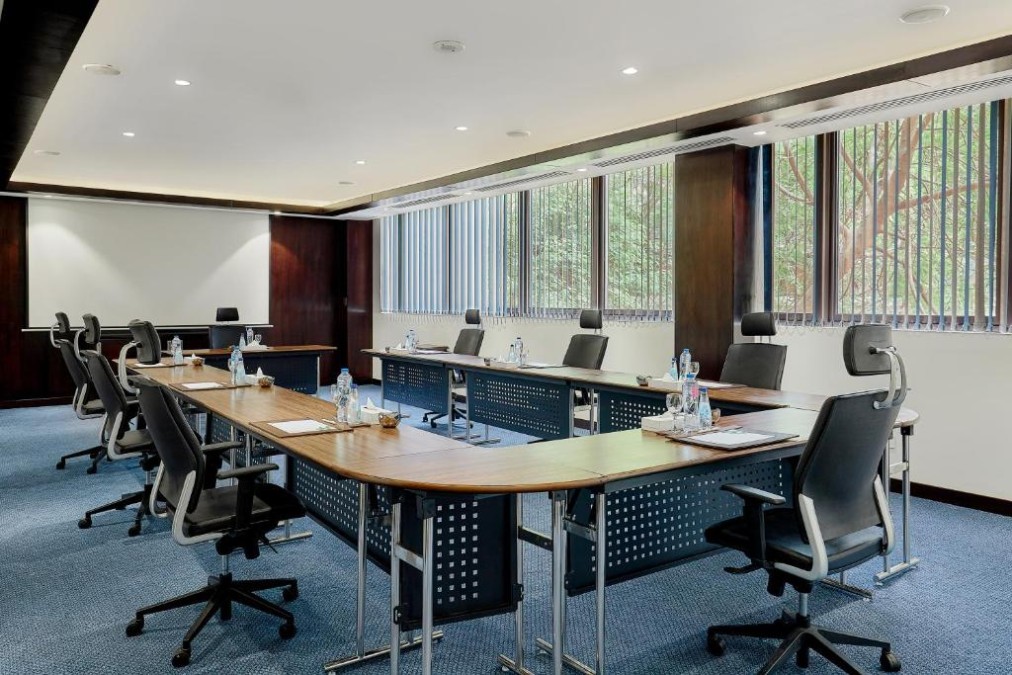 Salle de réunion en U avec chaises de bureau, écran de projection et bouteilles d'eau pour briefing de stage d'entraînement