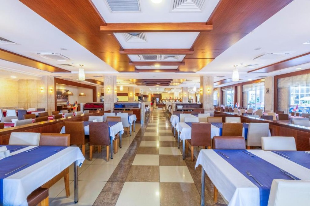 Salle de restaurant avec tables dressées, chaises rembourrées et allée centrale spacieuse.