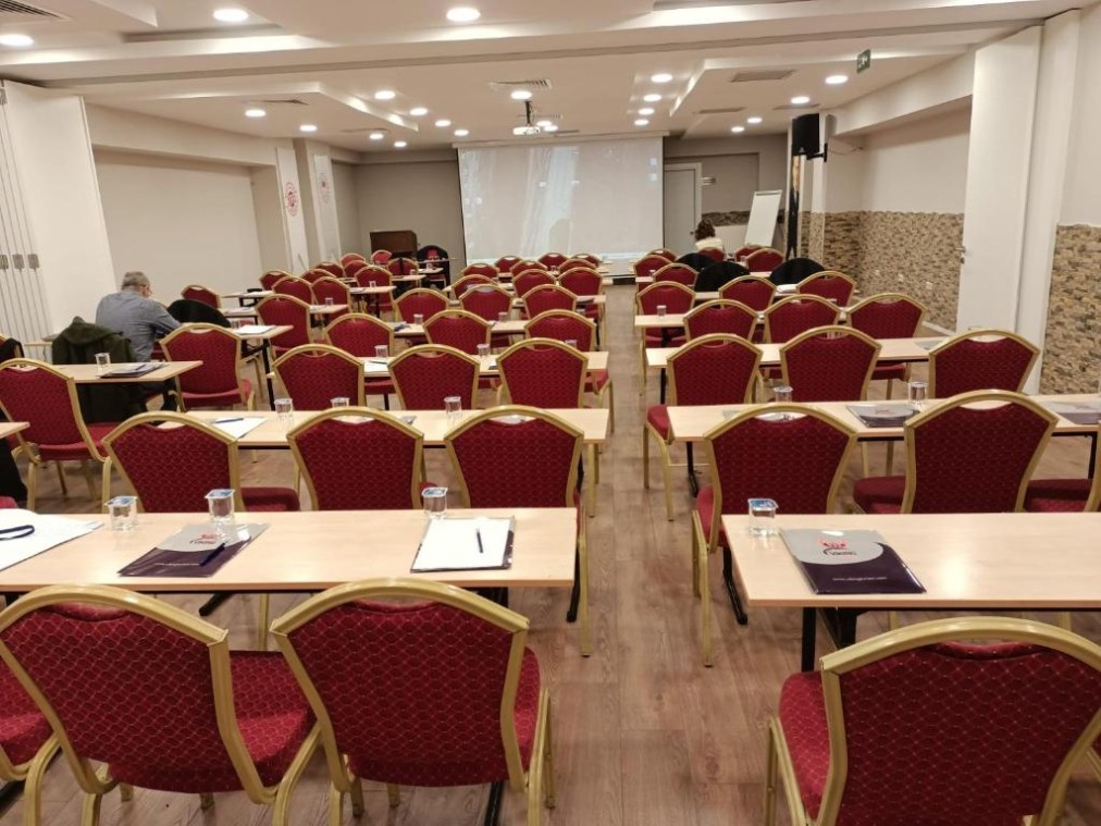 Salle de conférence avec disposition en classe, écran de projection et paperboard pour réunions d'équipe.