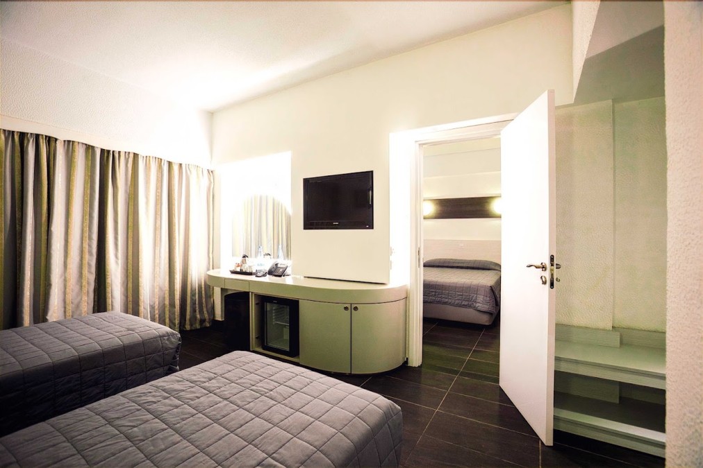 Chambre avec lits jumeaux, bureau, minibar et espace nuit séparé.