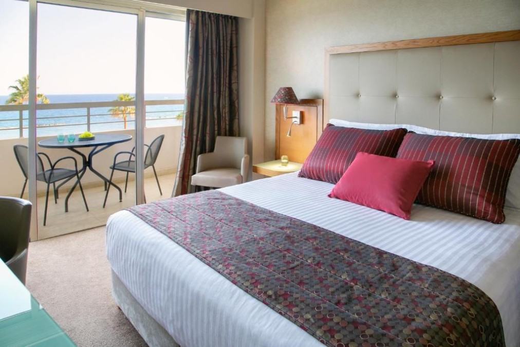 Chambre d'hôtes avec balcon vue mer, lit double et coin salon.