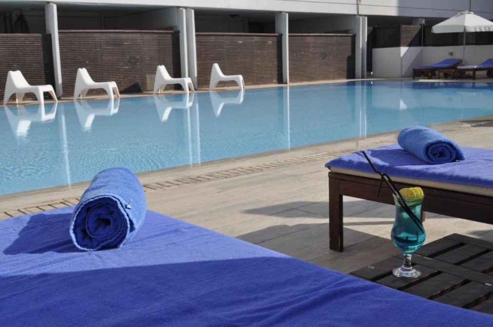 Piscine extérieure avec transats, serviettes et boisson au bord du bassin.