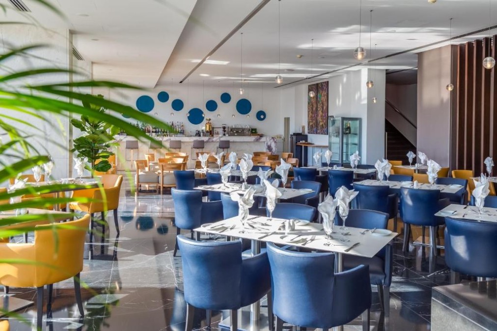 Espace restaurant avec bar, tables dressées et coin lounge.